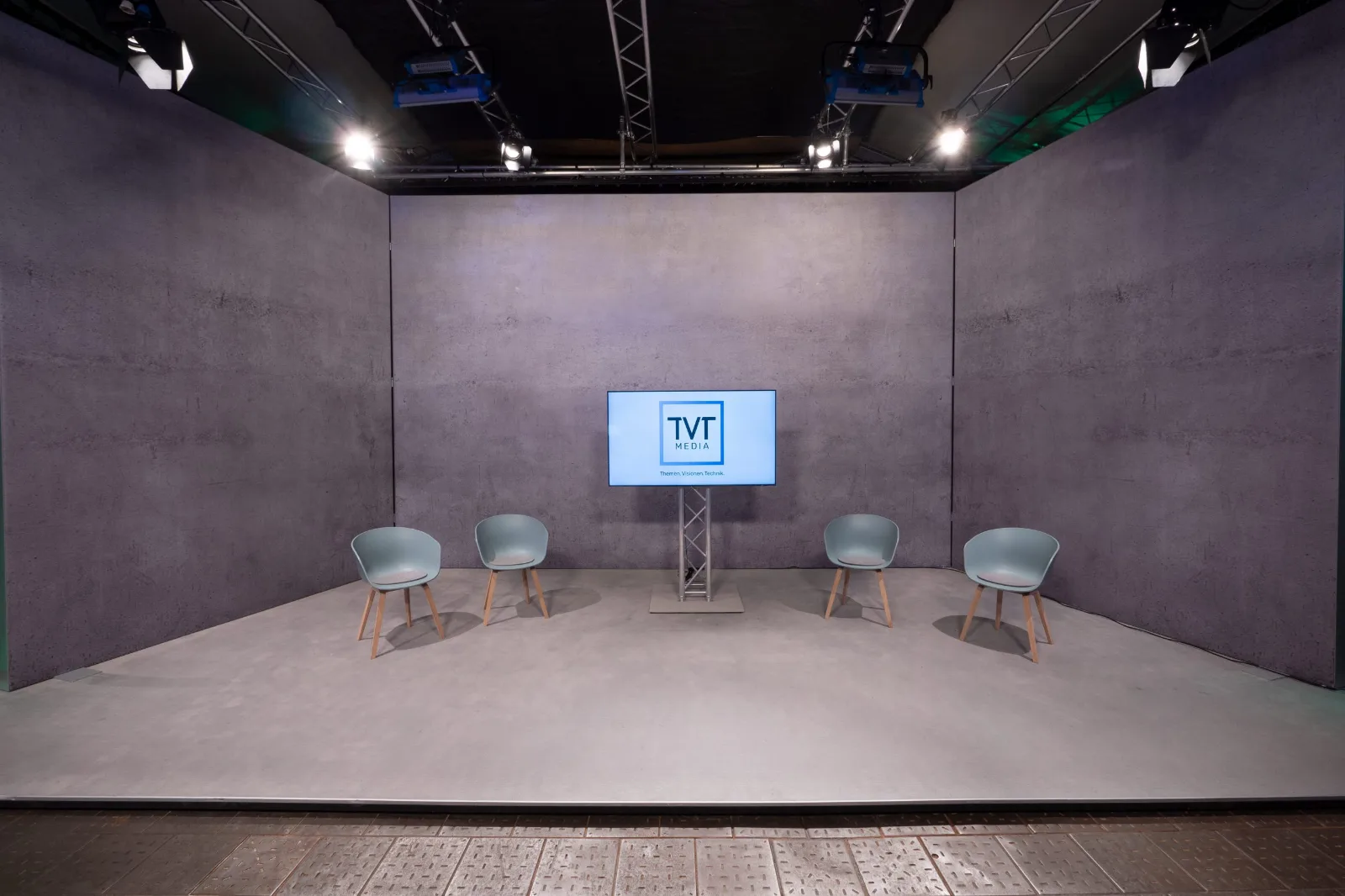 Studio von TVT.media mit Sichtbetonwand, Sitzgruppe und Monitor